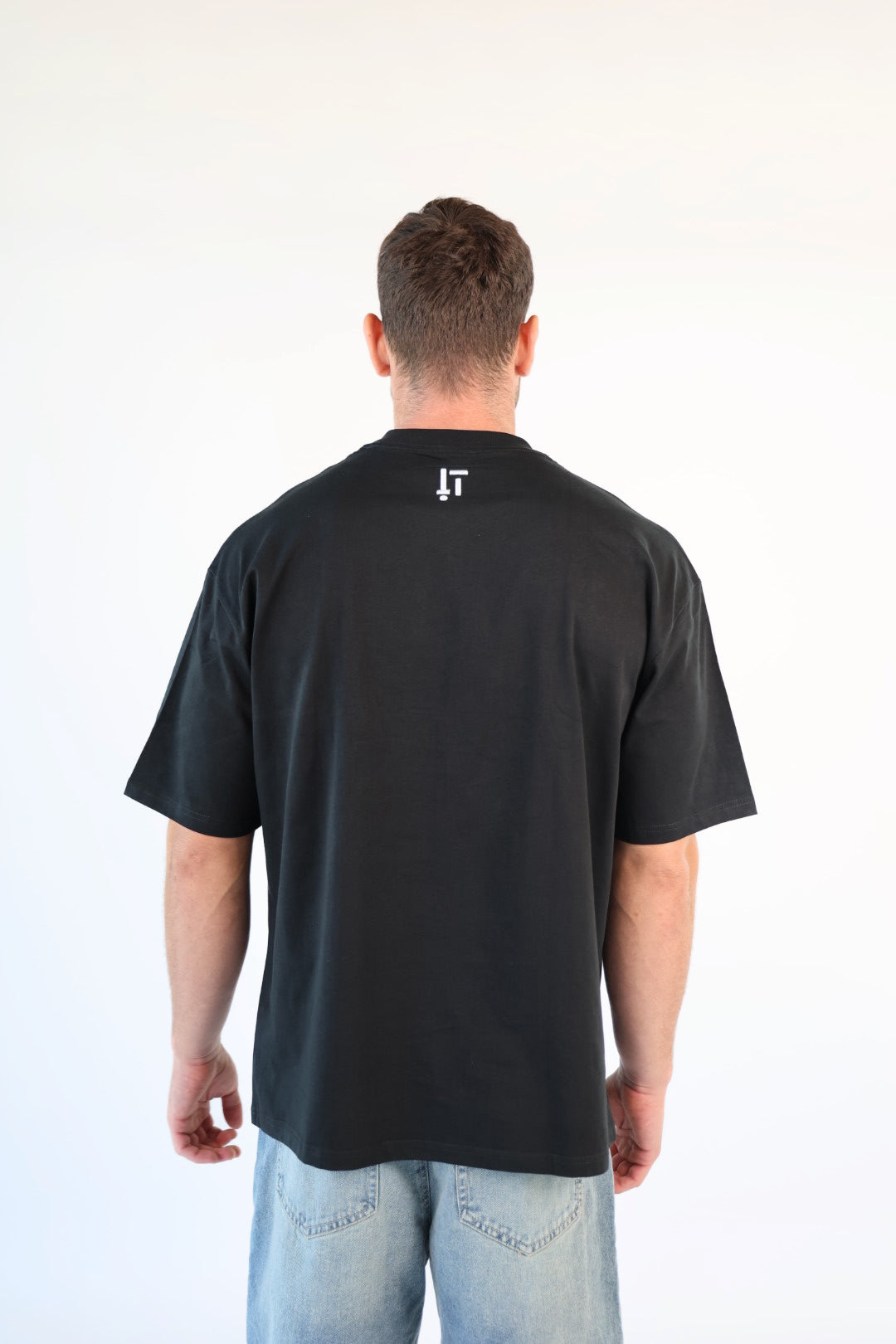 Man wearing a black t-shirt with a logo on the back against a white background