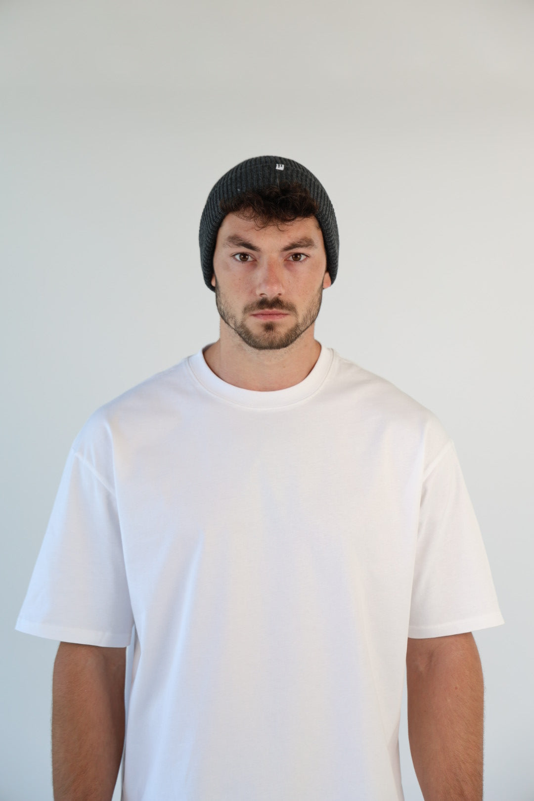 Person wearing a white t-shirt and black cap against a plain background
